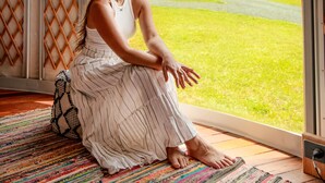A person sitting by a window with a view of a green landscape and a blue house. - NOOSA ECO RETREAT (Pomona)