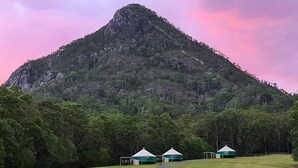 A mountainous landscape with a dirt path leading to yurts. - NOOSA ECO RETREAT (Pomona)