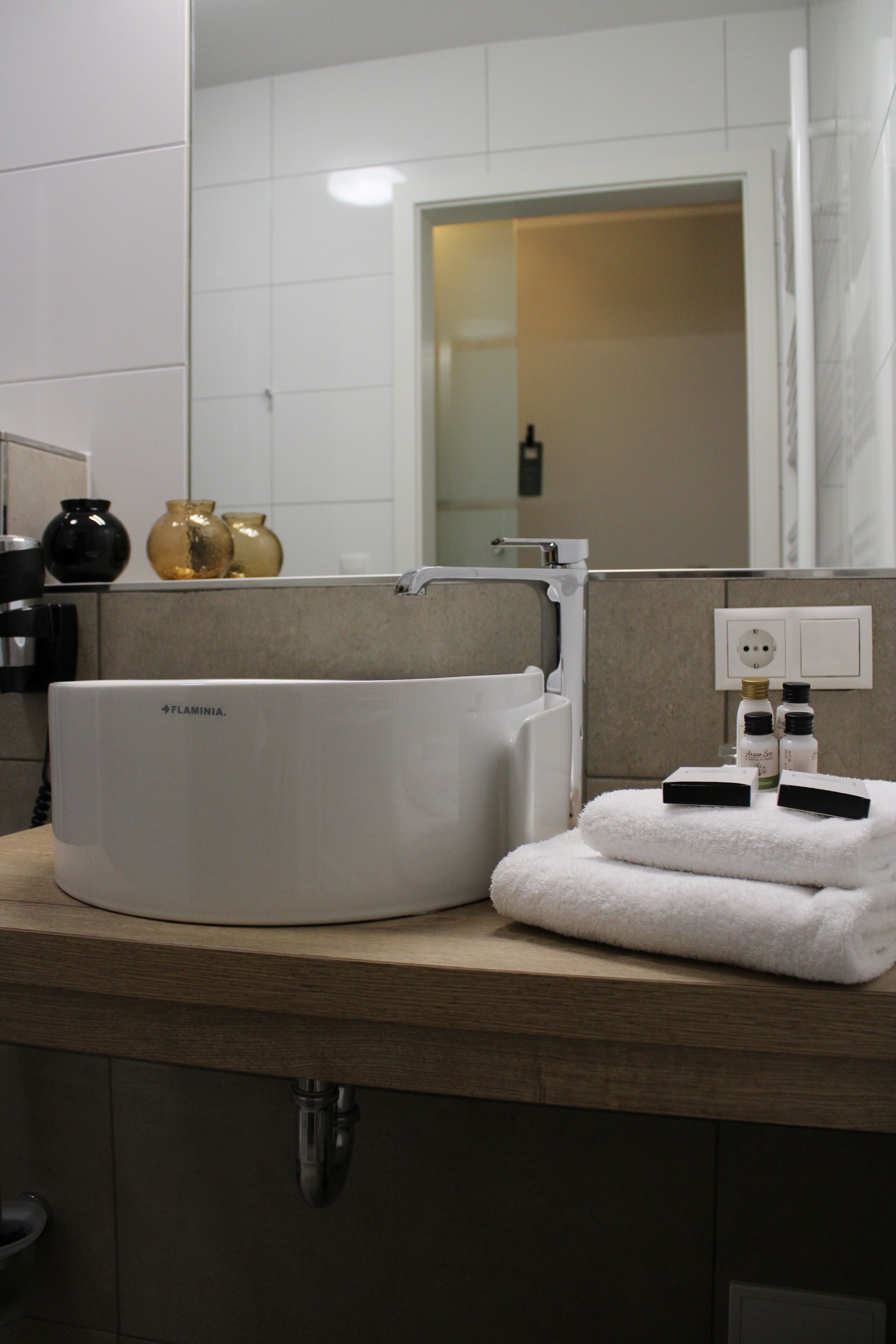 Ein modernes Badezimmer mit einer weißen Badewanne, einem Holzwaschtisch und einem Spiegel über dem Waschbecken.