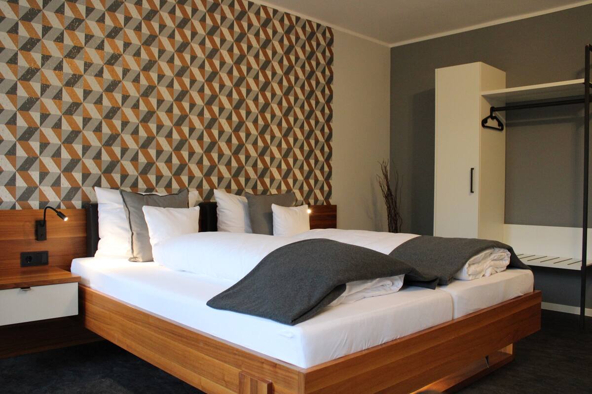 Ein modernes Schlafzimmer mit einer Wand im geometrischen Muster, einem hölzernen Bettgestell und einem eingebauten Kleiderschrank.