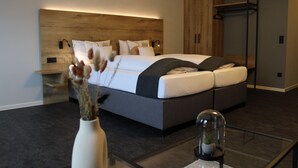 A modern bedroom with a large bed, bedside tables, a wardrobe, and a glass coffee table.