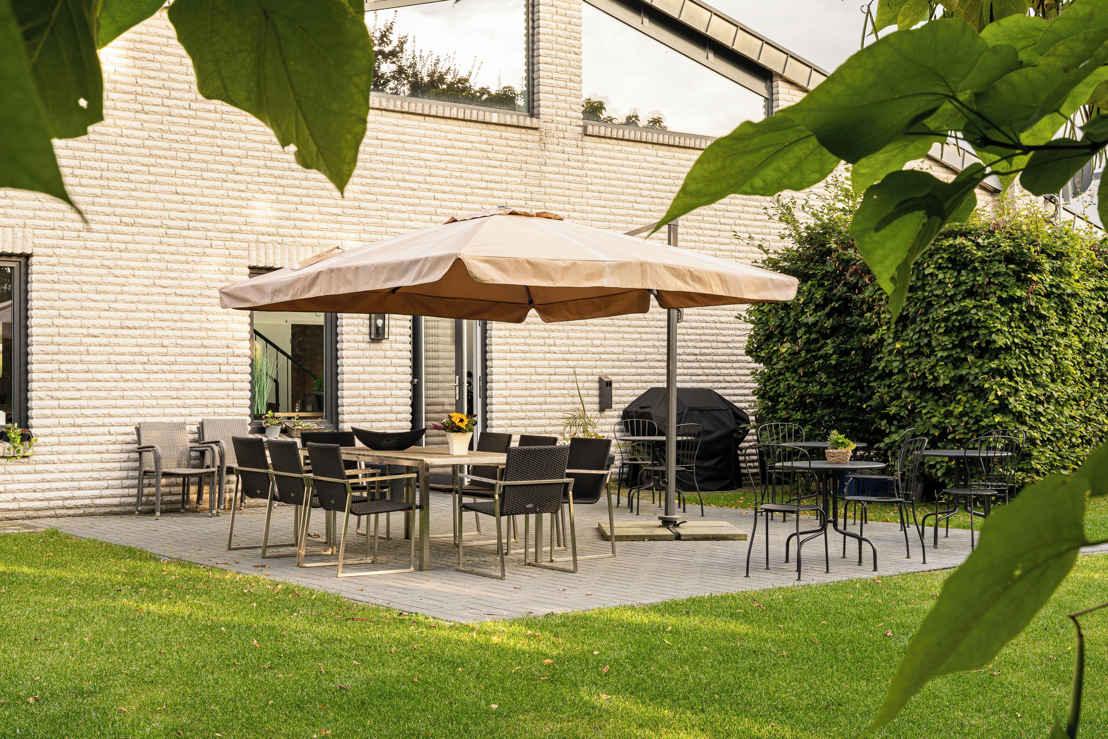 Un patio al aire libre con pared de ladrillo, una mesa con sillas y un paraguas grande.