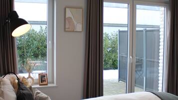 A hotel room with two beds, a window with curtains, a framed picture on the wall, and a view of the outside.