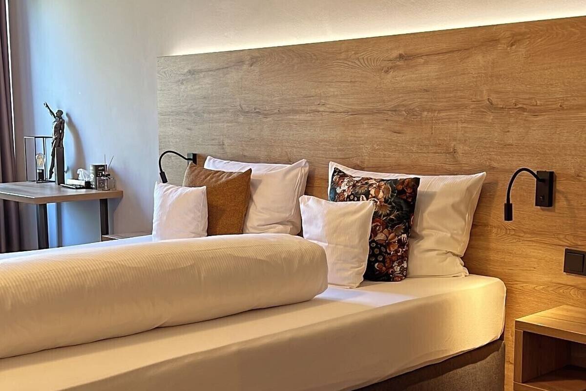 Ein modernes Schlafzimmer mit einem großen Bett, einem Holzkopfteil und einem Nachttisch mit Lampe.