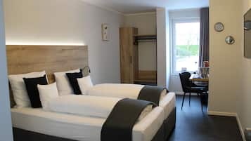 Ett hotellrum med två sängar, en sänggavel i trä, ett skrivbord och en stol.