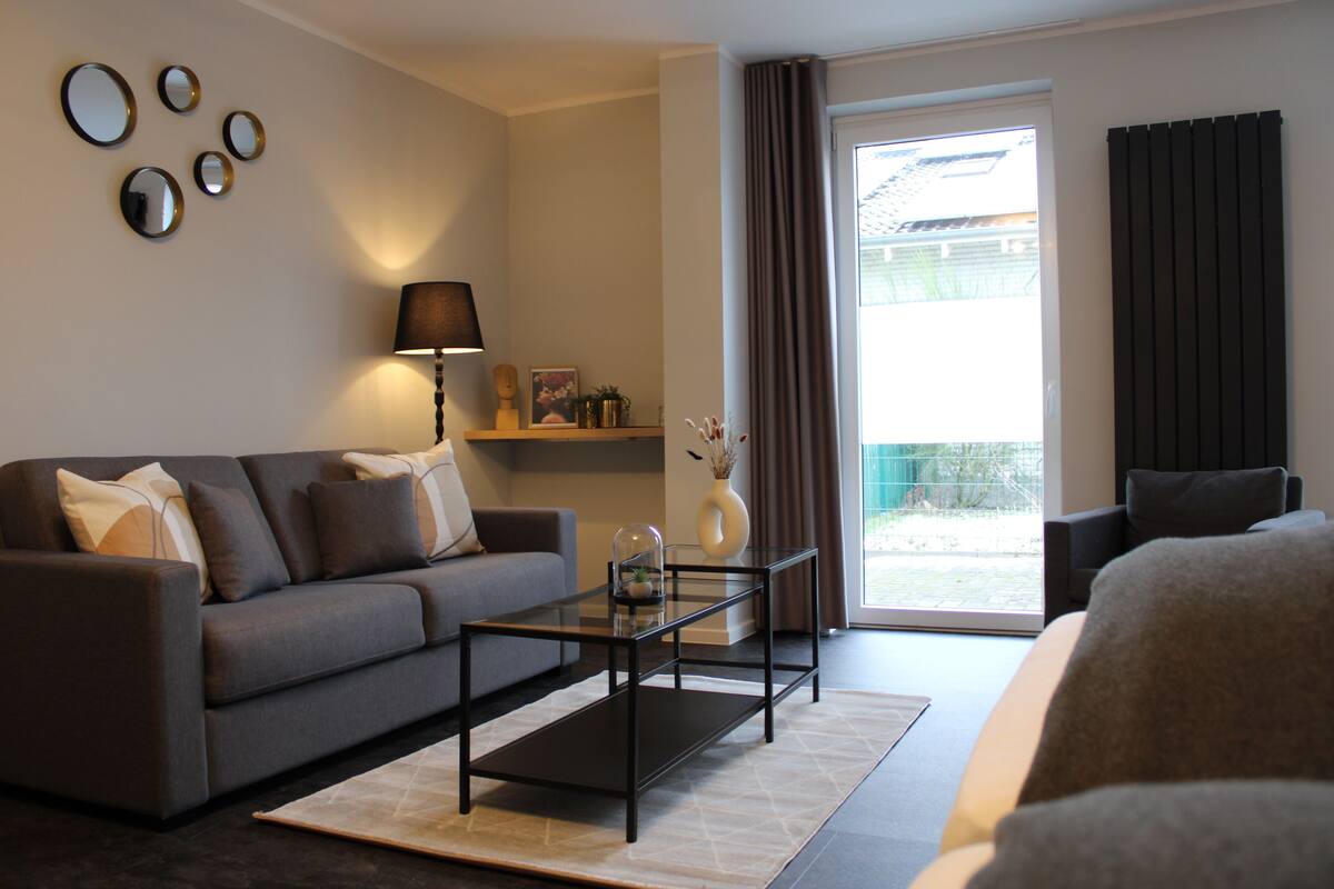 Ein modernes Wohnzimmer mit einer Couch, einem Glastisch und einer Lampe.