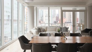 A modern living room with a large wooden dining table, black chairs, and a white sofa. - Luxury Loft Collection COMBO 02/03 | Terrace (Chicago)