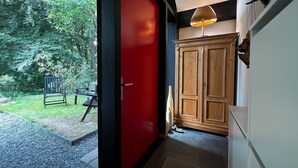 Un interior moderno con una puerta roja, un armario de madera y vista a un jardín.