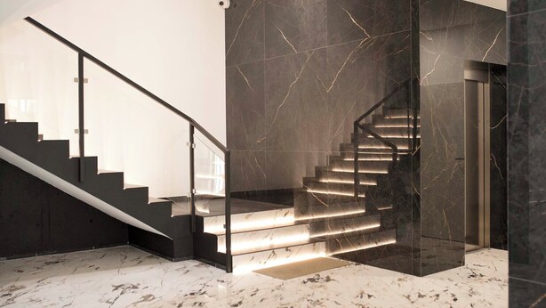 A modern staircase with glass railings and illuminated steps, leading to a dark-toned wall with a sleek design. - Cozy studio in charming Wrocław with WiFi access (Wrocław)