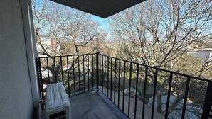 A balcony with a metal railing, an air conditioning unit, and a view of leafless trees and buildings in the background. - Cozy studio in charming Wrocław with WiFi access (Wrocław)
