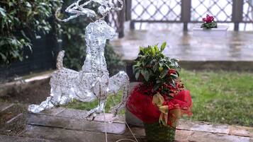 Une sculpture décorative représentant un renne en argent et une plante en pot aux fleurs rouges et jaunes, le tout posé sur une surface en pierre.