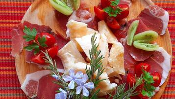 A wooden board with various meats, cheese, and vegetables.