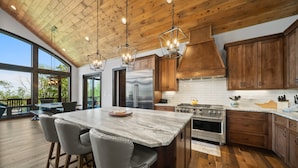 Una cocina moderna con armarios de madera, una isla grande y electrodomésticos de acero inoxidable.