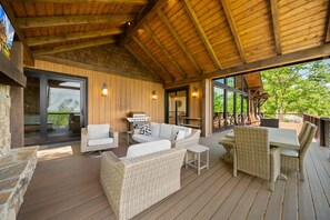Un patio techado al aire libre con mobiliario de mimbre, una mesa de comedor y una parrilla.