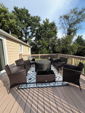 Een terras met tuinmeubilair, een ronde tafel en een gekleurd vloerkleed.