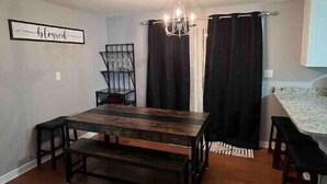 Un comedor con una mesa de madera, bancos y una araña.