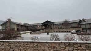 Un edificio con fachada de piedra, una entrada central y un área de estacionamiento.