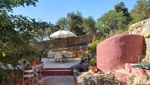 Un patio con mobiliario exterior, una pared de piedra y un paraguas grande.