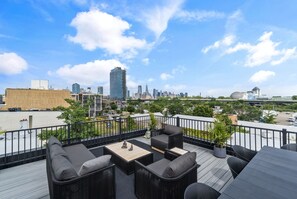 A rooftop terrace with outdoor seating, a city skyline view, and a Liberty Science Center in the background.