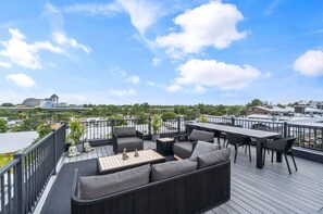 A rooftop deck with outdoor furniture, a view of the cityscape, and a Buddha statue.