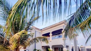 A modern two-story building with a central courtyard, surrounded by lush greenery and palm trees. - Luxe Apt #4the Retreat Apartments (Brusubi)