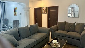 A living room with two grey sofas, a coffee table with a vase, and a mirror on the wall.