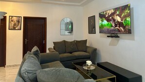 A modern living room with a sofa, a coffee table, and a TV mounted on the wall.