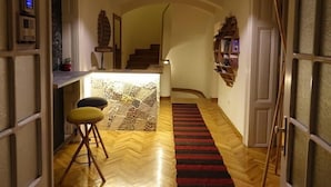 Un couloir doté d’un plancher en bois, d’une moquette rouge, d’un escalier et d’un coin bar avec des tabourets.