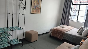 A room with a bed, a small table, a hanging rack, and a painting on the wall. - Casa Samor (Bogotá)