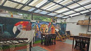 A covered outdoor seating area with a hammock, tables, and chairs. - Casa Samor (Bogotá)