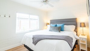 A bedroom with a bed, a ceiling fan, a window with blinds, a bedside lamp, and a nightstand. - Ocean View Rooftop Deck + Walk to Beach (Cardiff By The Sea)
