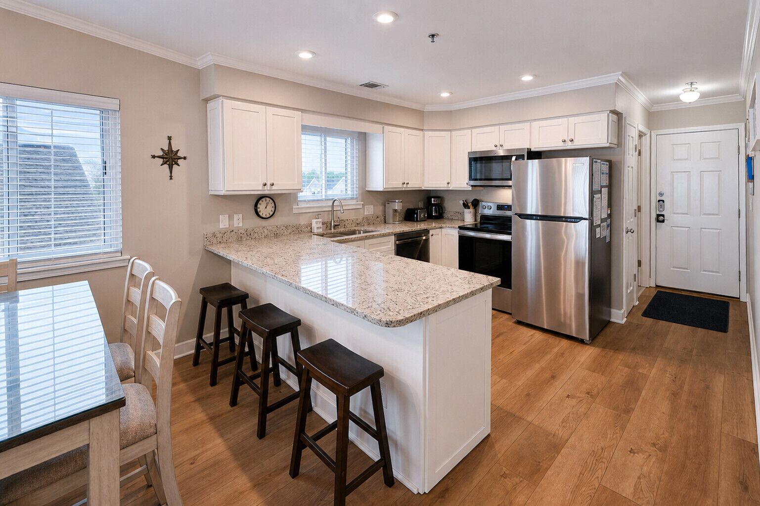 A modern kitchen with white cabinets, a stainless steel refrigerator, and a granite countertop.