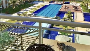 Un espace piscine d’hôtel comprenant plusieurs piscines, une vue sur la plage et un bâtiment doté de balcons.