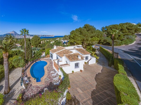Relax in a serene outdoor space with a swimming pool, surrounded by a charming traditional building and breathtaking coastal views.