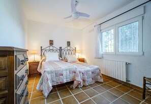 Two single beds with quilted bedspreads, a ceiling fan, and a dresser with multiple drawers.