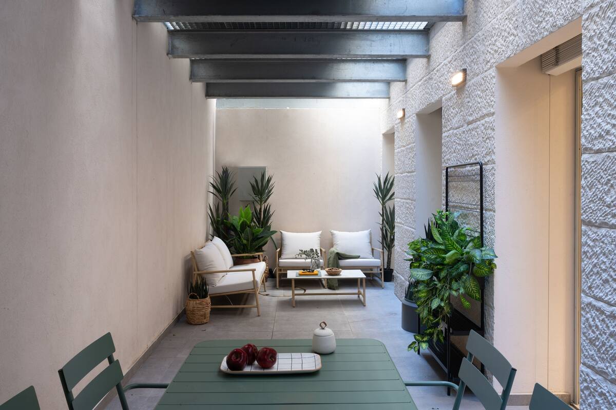 Un patio acogedor con una mesa, sillas, un sofá y plantas en macetas.