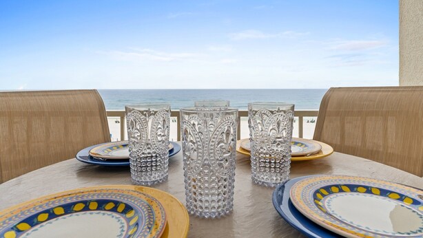 A table set with plates and glasses, overlooking a beach. - GD 410: Shimmering Sea - Sandy Toes, Cozy Condo, The Perfect Pairing! (Fort Walton Beach)