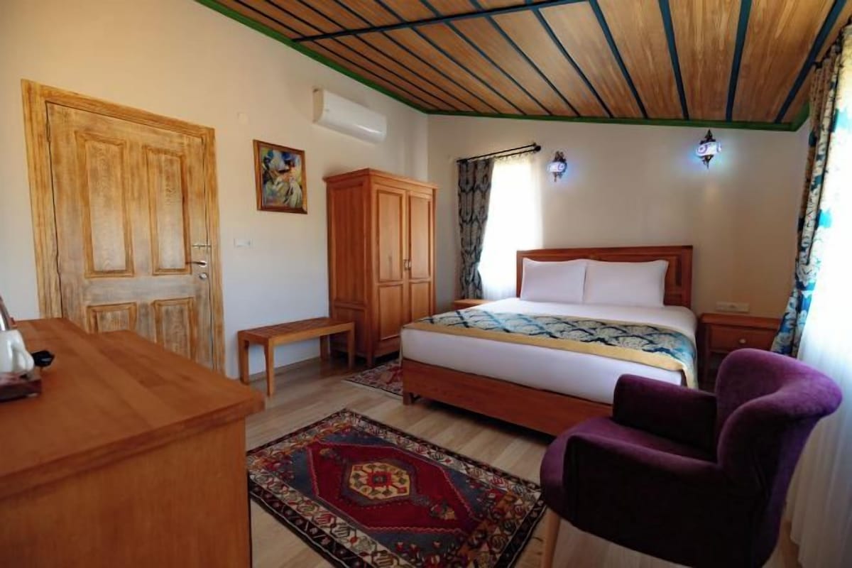 Quarto com cama de madeira, escrivaninha, cadeira e tapete estampado.