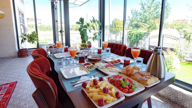 A breakfast table with various dishes, a coffee pot, and a view of the outdoors. - Cappadocia Villa Comfort (Nevsehir)