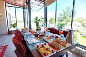A breakfast table with various dishes, a coffee pot, and a view of the outdoors. - Cappadocia Villa Comfort (Nevsehir)