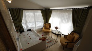 A room with a bathtub, two chairs, a small table with a vase, and a radiator. - Cappadocia Villa Comfort (Nevsehir)