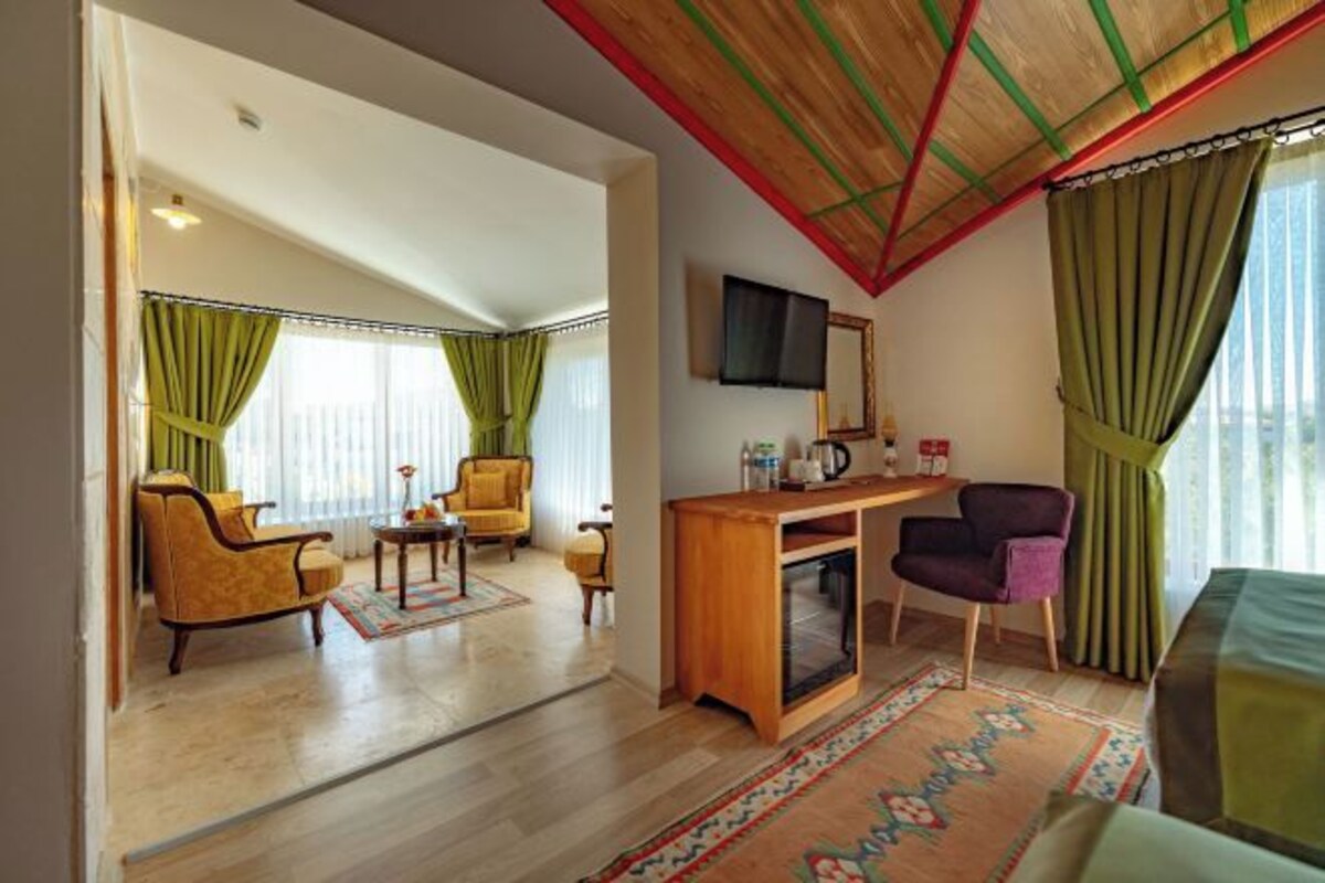Une chambre d’hôtel équipée d’un bureau en bois, d’une télévision, d’un canapé et d’un coin repas avec des chaises.