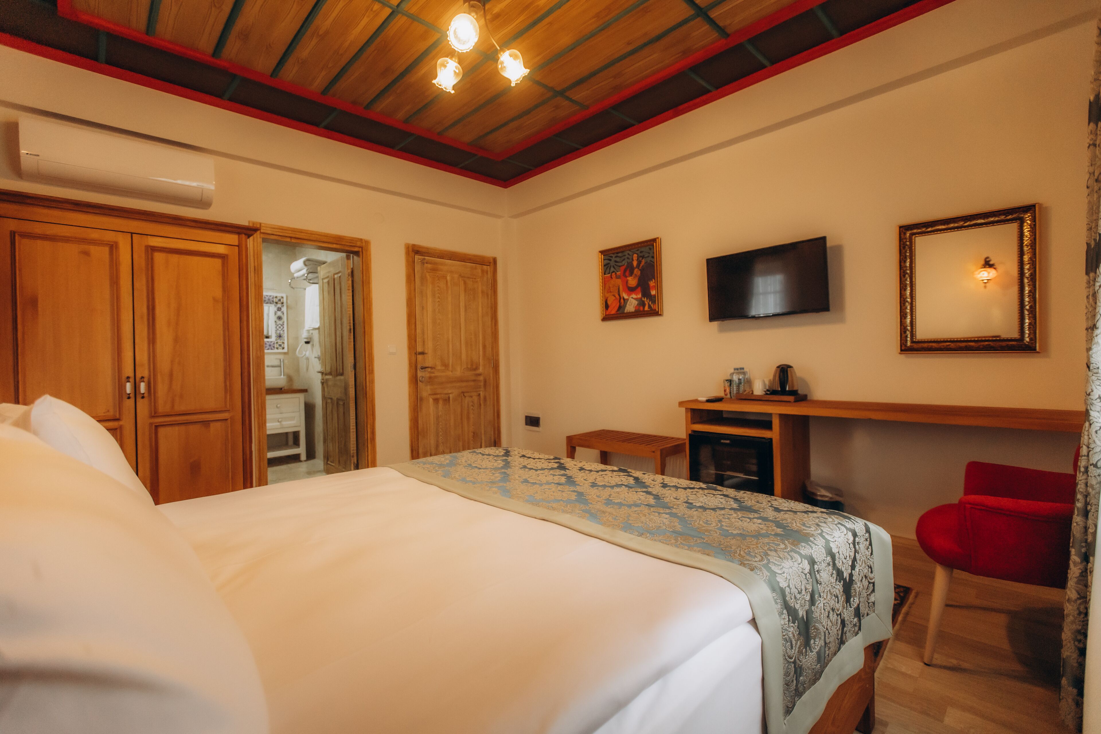 Una camera da letto con un letto, un armadio in legno, una televisione e una scrivania con una sedia.