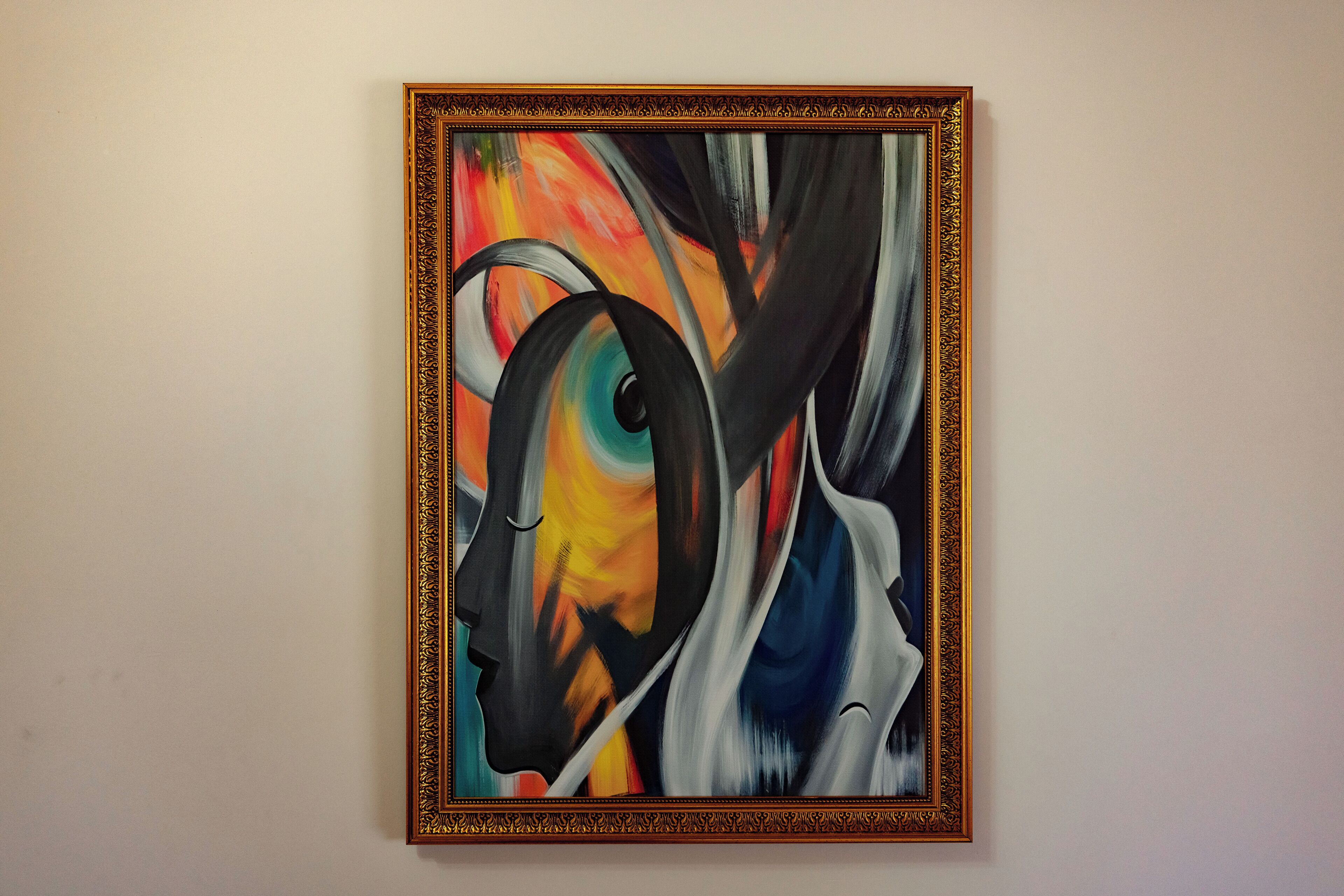 Une peinture abstraite encadrée, accrochée à un mur uni.