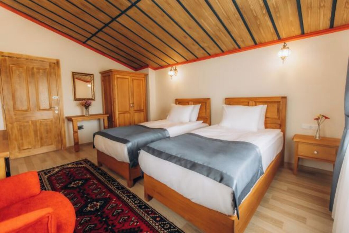 Une pièce avec deux lits en bois, une armoire en bois, une petite table et une chaise rouge.