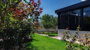 A modern building with large glass windows, a well-maintained lawn, and a variety of trees and shrubs. - Cappadocia Villa Comfort (Nevsehir)