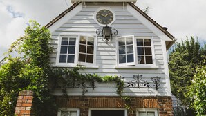 Un edificio blanco con un reloj, ventanas y una chimenea de ladrillo.