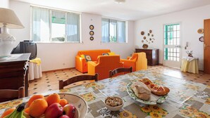 A dining area with a table set for two, a sofa, and a television in the corner. - Villa Giorgisa Casale pool sea view (Ugento)