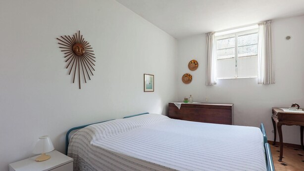 A bedroom with a bed, a nightstand, a dresser, a window with curtains, and a wall decoration. - Villa Giorgisa Casale pool sea view (Ugento)