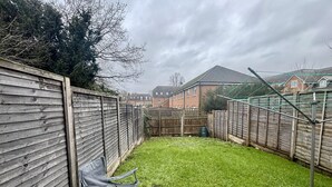 Ein Garten mit Holzzaun, Rasen und einer Metallkonstruktion.